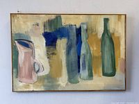 Front view of the framed abstract still life painting showing a pink pitcher and green bottles with a multicolored background.