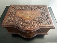 Top view showing carved floral motif and brass inlay floral design on lid