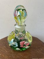 Front view of the trumpet flower glass perfume bottle paperweight with colorful interior flowers and bubbles.