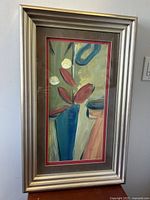 Framed abstract floral still life art print hung on a wall showing the entire piece vertically.