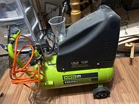 Side view of the Power It! air compressor showing hose, air tool head, and pressure gauges.