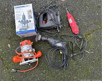 All five electric construction tools displayed together on pavement including boxed Dremel plunge router base, jigsaw, drill, rotary tool, and compact router.