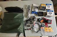 All items laid out on table: camera, bag, filters, adapter, tripod, charger, cables, cloth