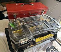 Photo showing the two toolboxes stacked, red metal toolbox with top handle and Stanley plastic toolbox with clear lid