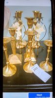 Photo of assorted brass and brass/resin candle holders with varied shapes, some ornate, grouped together on a surface.