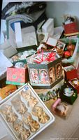 Photo of assorted Christmas ornaments and decorative boxes including a black box with holiday artwork, red and white plastic ornaments, and various other decorations.
