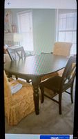 Photo of black wooden oval farmhouse style dining table with turned legs in room with chairs and windows