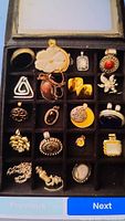 Box of assorted pendants in a compartment tray, showing a variety of stones including pearls, smoky quartz, agate, mother of pearl, and coral, with metal types 925 Sterling silver and 14kt gold