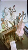 Four metal and wood sculptures depicting musicians with instruments, including saxophone, trumpet, double bass, and guitar, displayed together on a flat surface.
