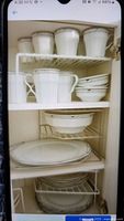 Shelves with stacked white china cups, saucers, plates, and bowls.