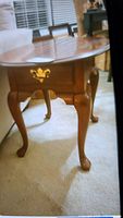 Side view of wooden Queen Anne style side table showing curved legs and drawer.