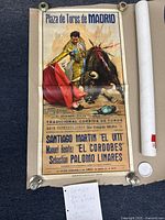 Full frontal view of the vintage 1968 bullfighting event poster with matador and bull illustration alongside mailing tube and weight for display.