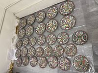 Top view of the 28 porcelain plates arranged in rows showing the detailed floral pattern and varying sizes.