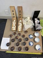 Top-down view of cups and bowls spread out beside wooden boxes and papers on a mat.