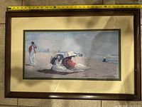 Framed painting showing females on a beach with umbrellas, set in a dark wooden frame with double matting.