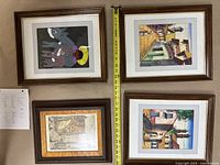 Photo of four framed artworks arranged on floor, highlighting sizes and frame styles