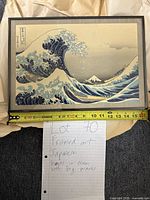 Front view of framed artwork with measuring tape indicating approx 16 inch width, showing print of crashing waves