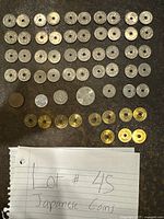 Top view layout of multiple Japanese coins showing several rows of silver-toned coins with center holes, brass-colored coins at bottom and a handwritten note indicating lot number and description.
