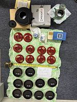 Photo showing all items including green teapot, red saucers, black soup bowls with lids, sake cups, and boxed items arranged on fabric.