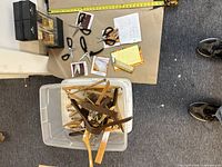 Plastic bin filled with assorted used wooden clothes hangers and multiple pairs of scissors with black handles on table.