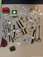 Full overview photo showing the entire lot including coins, watches, jewelry, pouches, and spoons.