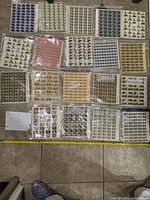 Multiple sheets of stamps laid out on floor showing various designs and denominations.