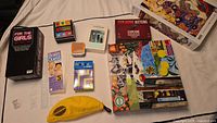 Photo showing 1000-piece puzzles, Exploding Kittens game, MENSA for Kids, Brain Quest and Banangrams card games, mini microphone in yellow pouch.