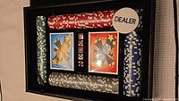 Photo of open black faux leather case containing poker chips in four colors, two decks of playing cards, red dice, and dealer marker.