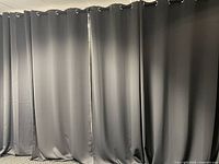 Full-width view of five gray curtain panels hung on rod