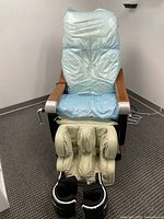 Front view of the electric massage chair showing the foot and calf massager section. Chair is covered with blue protective wrap.
