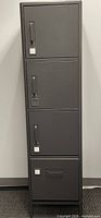 Front view of the grey metal locker showing three locked compartments and a bottom drawer with handle.