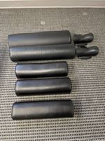 Four black foam-covered therapeutic pillows with two small matching support pieces on a woven surface.