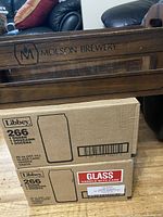 Wooden Molson Brewery crate with logo visible on the side, cardboard cases of Libbey 266 beer glasses stacked below it.