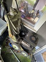 Front and top view of the commercial lawn vacuum showing the pull start engine, 'Billy GOAT' brand, and fabric collection bag filled with debris.