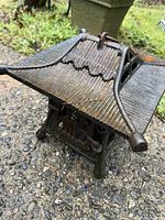 Close-up angled view of cast iron candle holder showing textured pagoda roof with finial and ridge details.