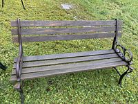 Full front view of cast iron garden bench with wooden slats showing overall condition and structure.