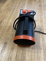 Front view of the Honeywell portable heater showing black and orange cylindrical body with control knobs and power cord.