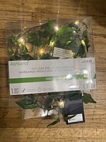 Ivy leaf pre-lit garland packaging showing brand and product information on wooden surface.