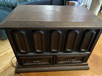 Wooden jewelry box closed, showing carved front panel design and two small drawers
