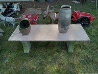 Full view of marble table with two ceramic plant pots placed on top, showing the table's concrete supports.