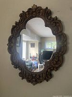Photo of an ornate wall mirror with carved decorative frame and clear glass.