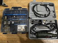 Top-down photo of rotary tool and accessories in open plastic case; includes power cord and flexible shaft attachment.