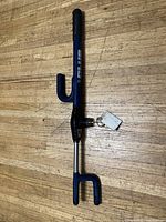 Image of The Club steering wheel lock lying on a wooden surface showing the full lock including hooks and key attached.