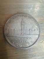 Close-up photo of 1939 Canadian silver dollar coin showing Parliament buildings and Peace Tower on reverse with inscriptions around edge.