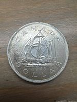 Front side of 1949 Canadian silver dollar coin showing Bluenose schooner and date.
