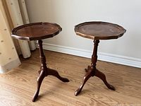 Photo of two wooden Bombay Company plant stands showing full view from the front in natural light on hardwood floor.