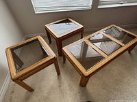 Three tables: one long coffee table and two square end tables on carpet under window.