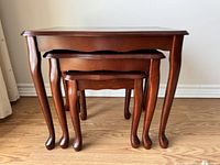 Three wooden nesting tables arranged side by side showing the leg design and finish.