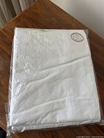 The white embroidered cotton duvet cover folded and packaged, showing the overall appearance and embroidered floral pattern.