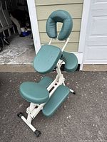 Full view of the portable Earthlite massage chair with face cradle, armrest, knee rests, and footrest outdoors.